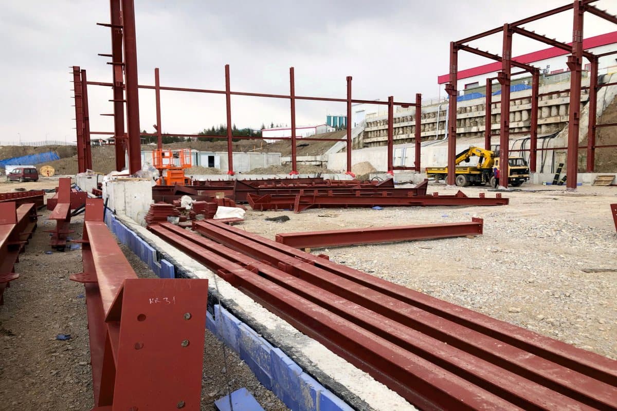 Steel beams lined up along the foundation and frames rising
