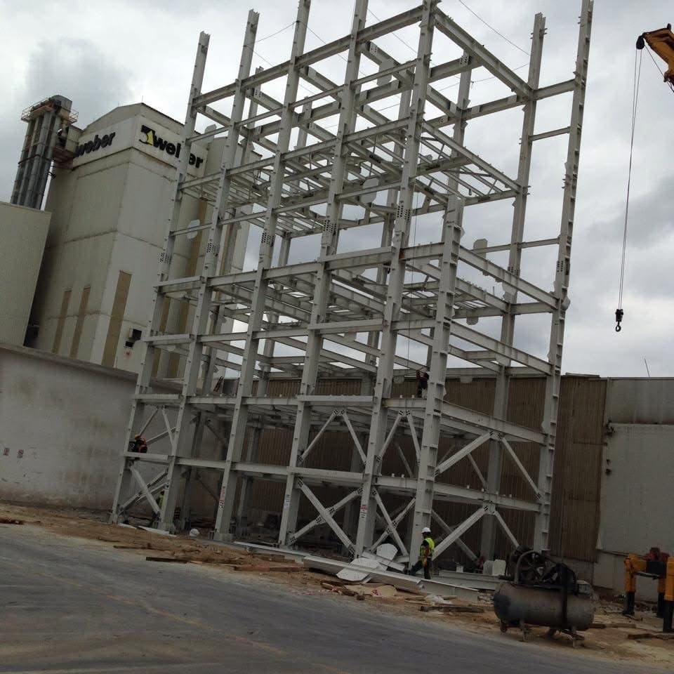 Steel silo support structure rising in front of the Weber plant