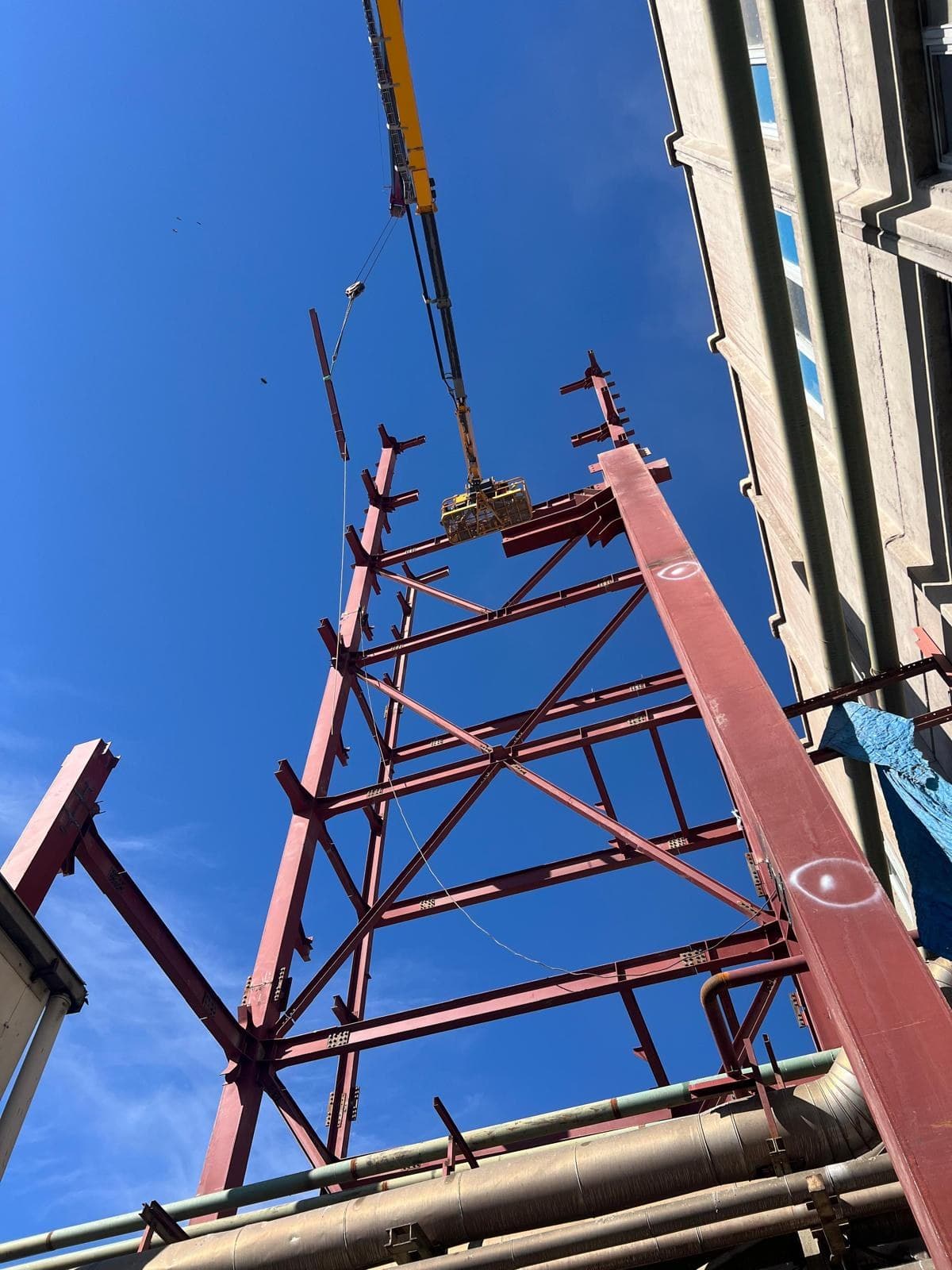 Red steel transfer tower being set in place by crane