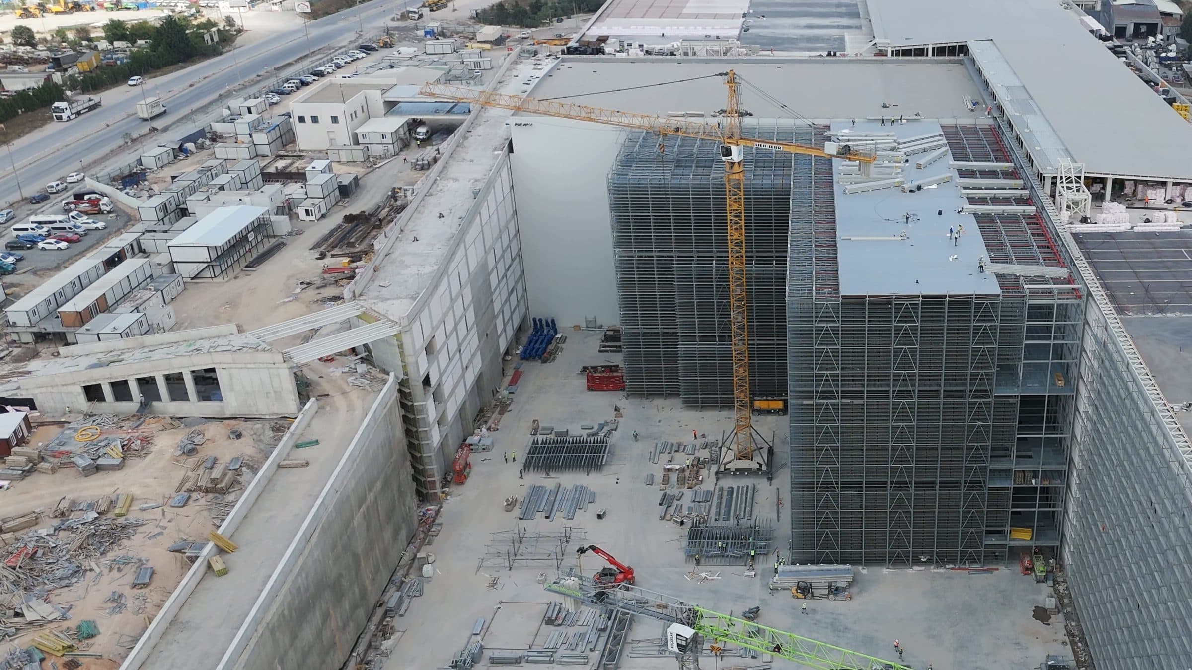 Aerial view of the automated warehouse rack blocks rising at the Ekol Logistics site, with a tower crane