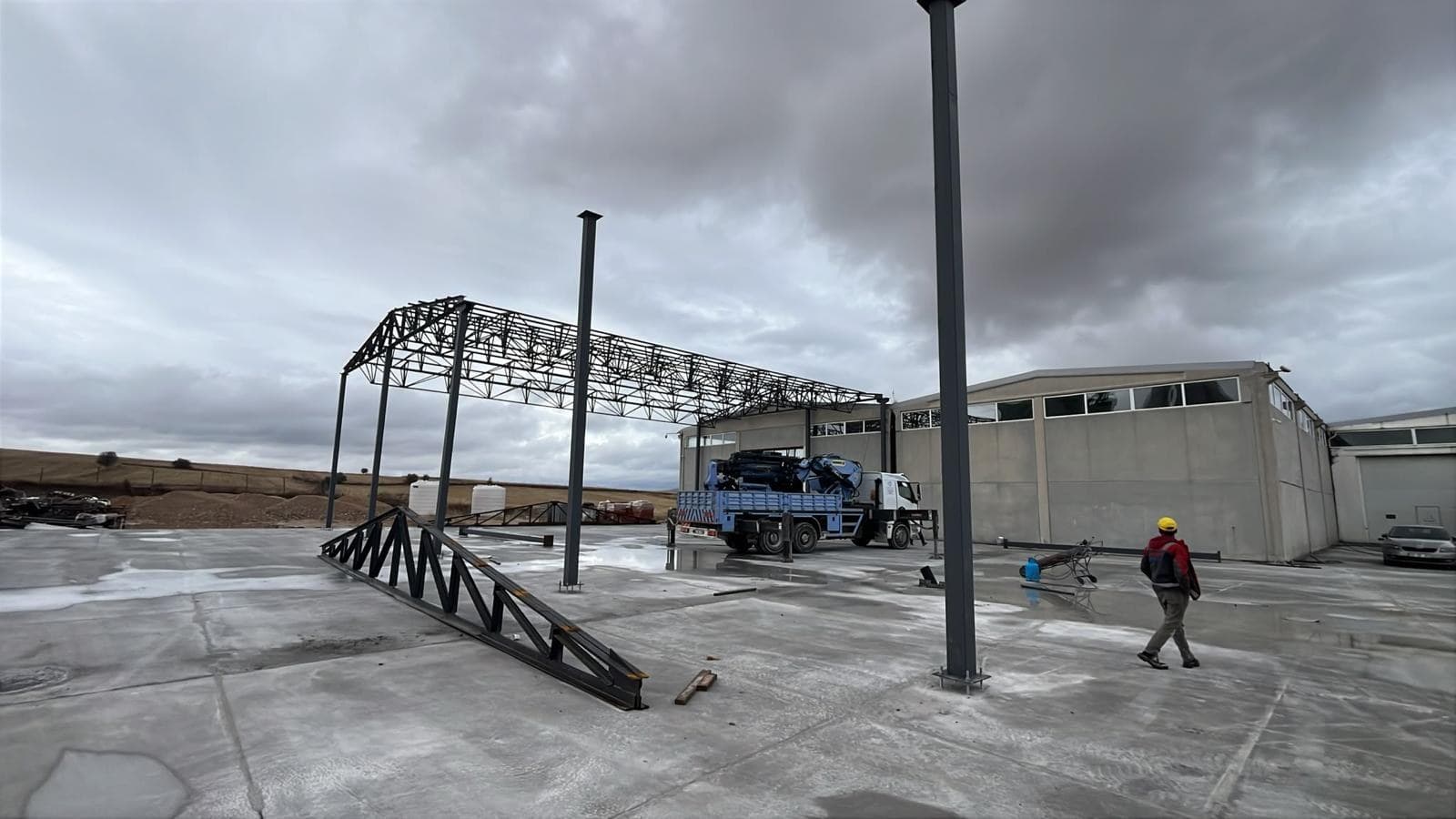 Steel roof truss waiting on the ground while the columns are erected