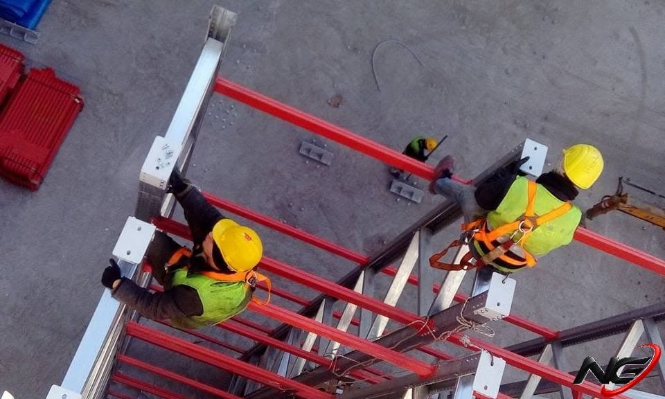 Erection crew with helmets and harnesses at the top of the racking, aerial view